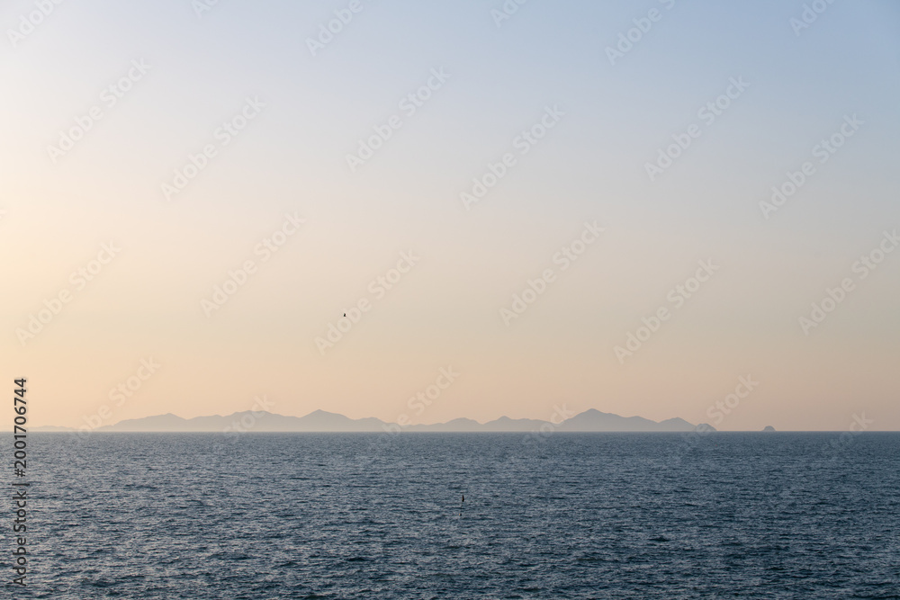 Fototapeta premium Distant Mountainous Island Silhouettes on the Blue Ocean Horizon