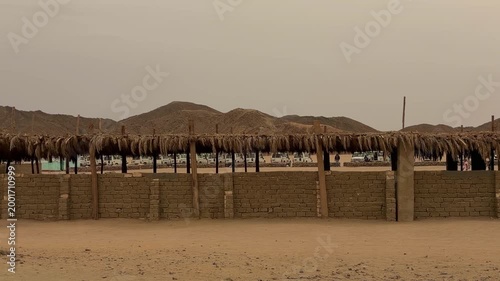 Series Of Rustic Strawroofed Cottages Arranged Along Mountain Landscape In Distance