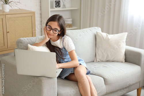 Little schoolgirl using sofa on sofa at home