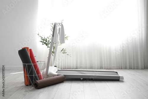 Treadmill with towel and fitness mats in light room