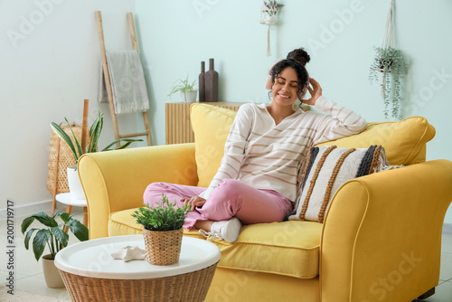 Beautiful young happy African-American woman in headphones listening music on...