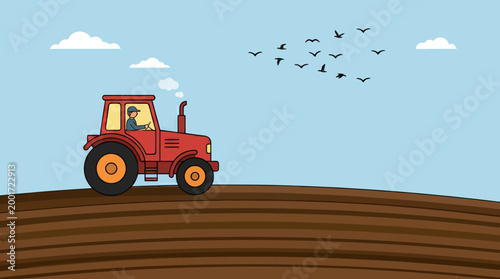 A tractor drives on a plowed field with birds flying overhead on a sunny day with clouds.