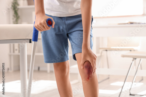 Little boy with injured knee and crutch in clinic, closeup