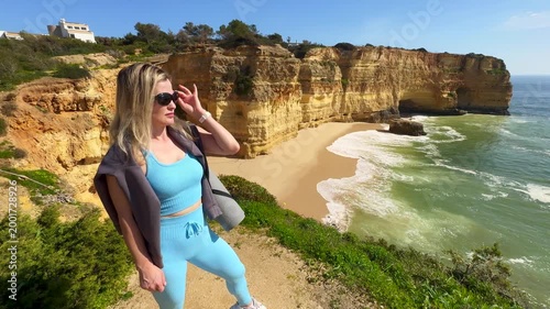 Woman Yoga Mat Beach - A woman in leggings carries a blue yoga mat while standing on a concrete pier overlooking the ocean.