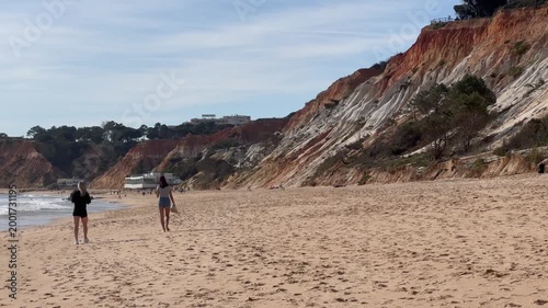  Caucasian mother and daughter walking on the beach on a sunny day 