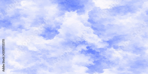 A beautiful summer day features bright white fluffy cumulus clouds floating across a high blue sky, creating a light and airy cloudscape in the sunlit atmosphere