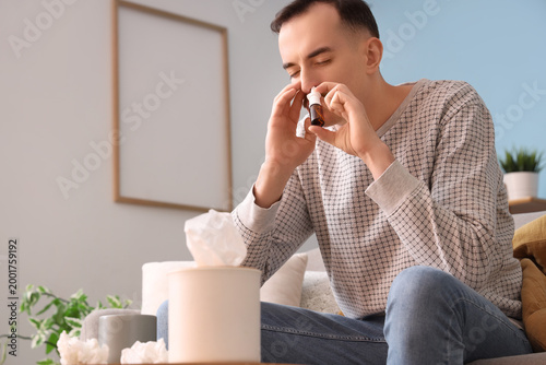 Tableau sur toile Ill young man using nasal drops at home