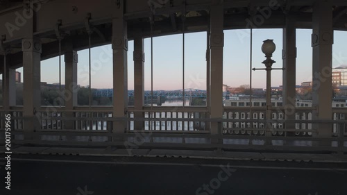 View from the High Level Bridge in Newcastle looking west at dawn, framing the River Tyne and distant Metro Bridge through historic iron pillars.
