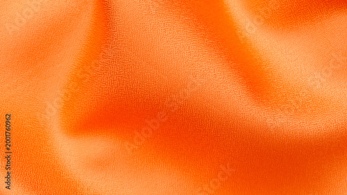 Bright orange fabric draped with folds showing smooth texture and shine in natural light