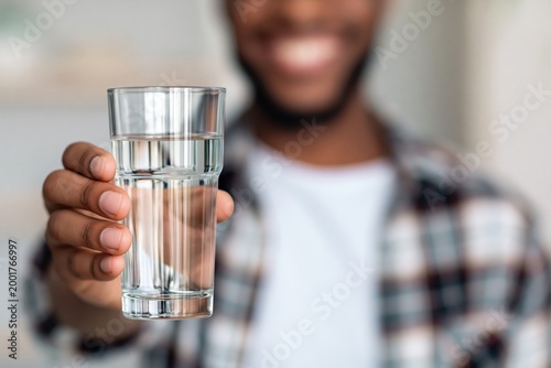 Man holding out a refreshing glass of clean drinking water, promoting daily hydration for a healthy lifestyle
