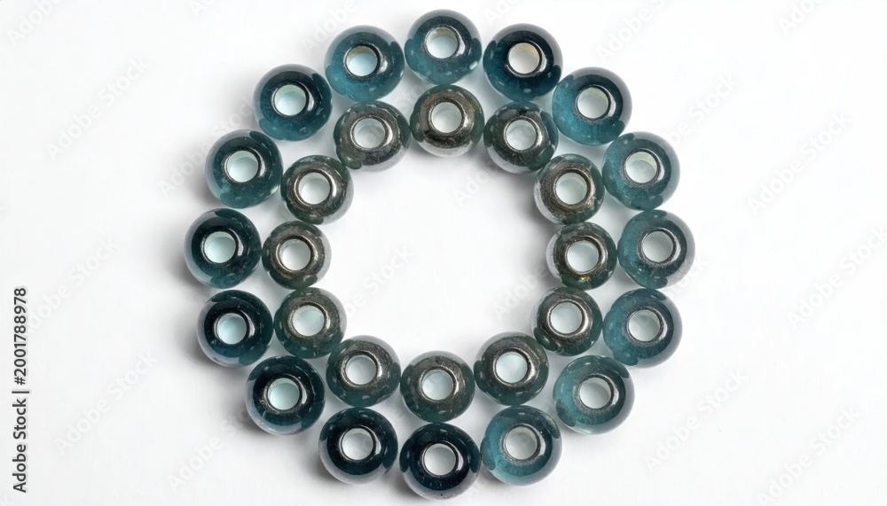 Fototapeta premium Round teal and dark blue glass beads arranged in a circular pattern on a white background