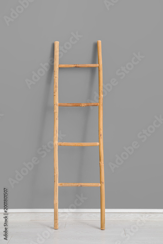 Wooden ladder near grey wal...