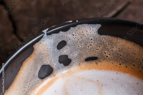 Obraz na płótnie Macro view showing comforting warm coffee beverage inside dark cup with milky fo