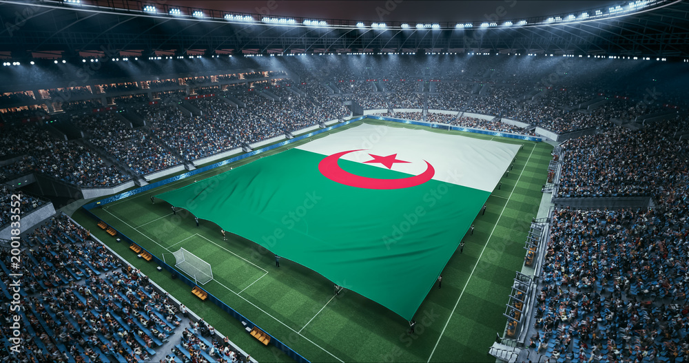 Obraz premium Professional Stadium Soccer Game Championship With Flag of Algeria Spread Across the Pitch Before Football Match Start. Cheering Crowds of Fans Surround the Field. Aerial Wide Shot