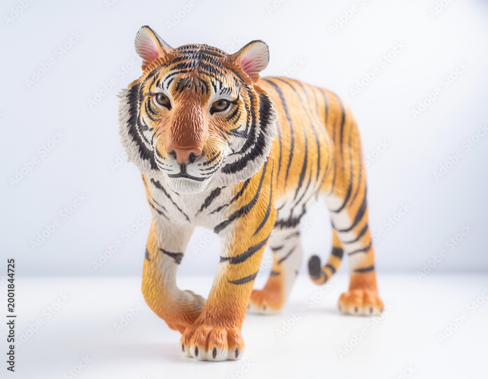 Obraz premium Majestic tiger figurine captured in a studio setting, showcasing its detailed features and vibrant stripes on a clean white background