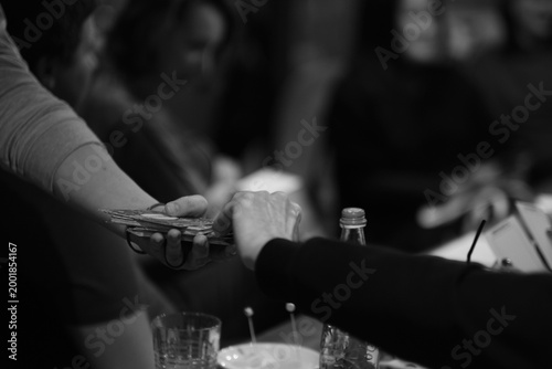 Hands exchange illustrated cards across a table during an intimate evening workshop, with cups and a microphone nearby. Creative coaching, storytelling, and peer support encourage open dialogue.