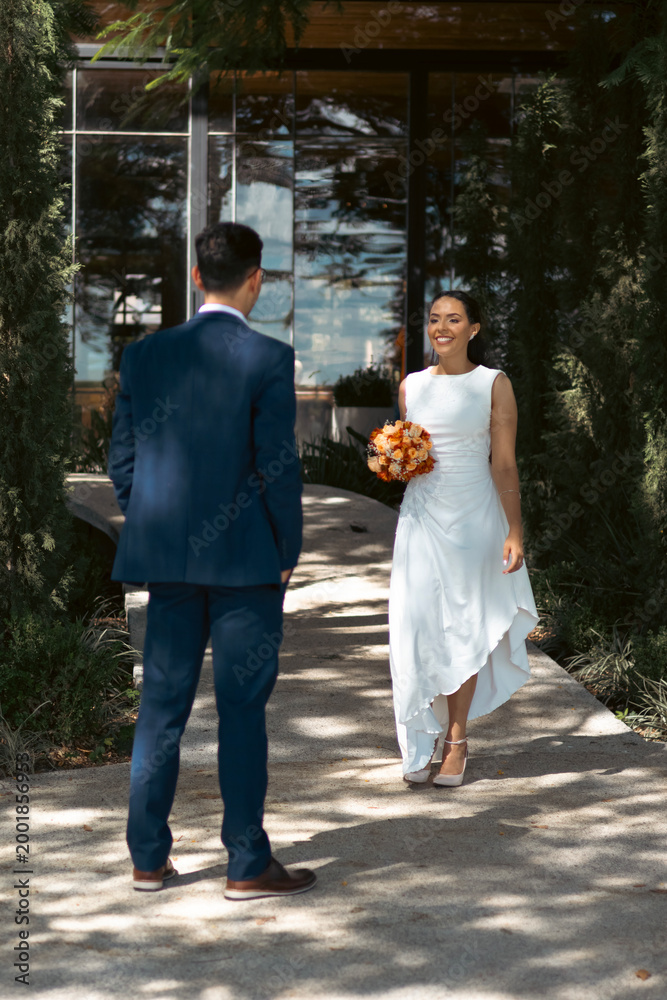 Fototapeta premium Happy bride and groom walking and embracing outdoors in romantic wedding setting
