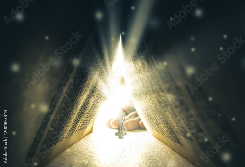 A silhouette of a man walking toward a bright light, toward a huge human palm, through a huge ancient book. The concept of religion, God, soul, faith, light at the end of the tunnel, choice.