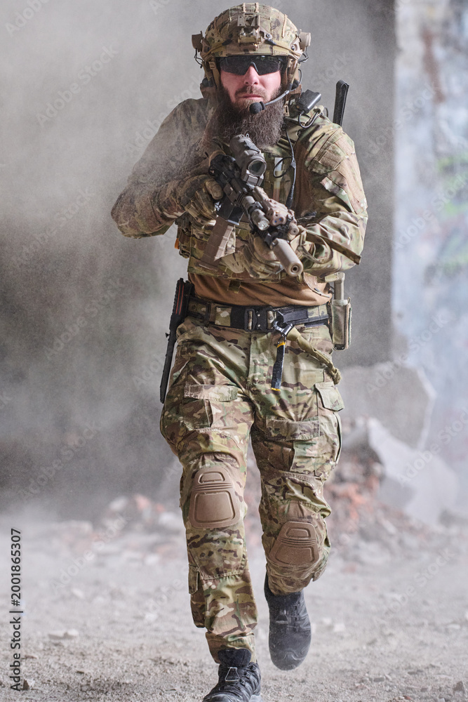 Fototapeta premium Armed Soldier In Tactical Gear Running Forward With Rifle During Urban Military Operation