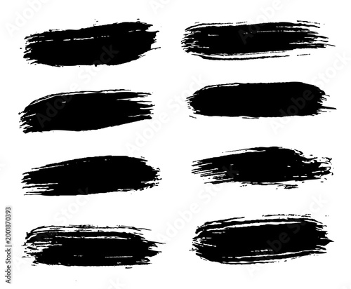 Set of eight irregular black brush marks on white background. Each stroke differs in shape and texture. Minimalist yet expressive visual accent.
