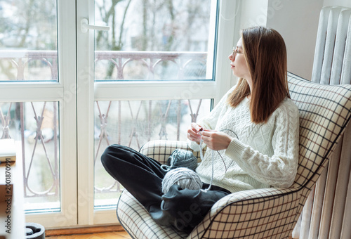 Woman knitting yarn looking out window relaxing