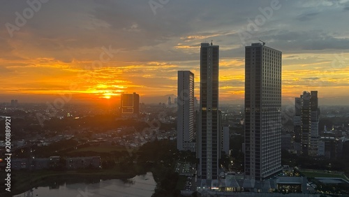 Schilderij op canvas Breathtaking golden sunset over a modern city skyline with tall residential skyscrapers