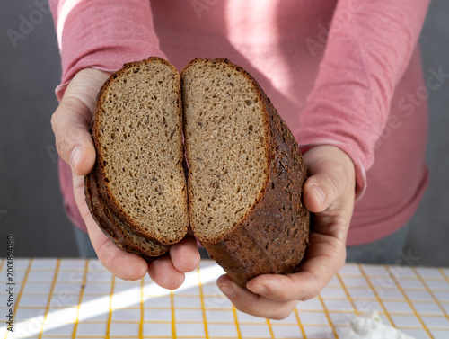 person cuts black bread on wooden board with knife. Sourdough rye bread with crispy crust. Bakery products. homemade cakes, yeast-free sourdough bread. Wholesome and healthy food. bakery.