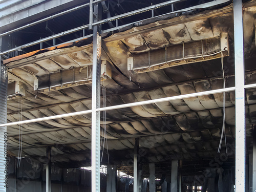 Damaged warehouse interior after a devastating fire, showing structural damage and soot