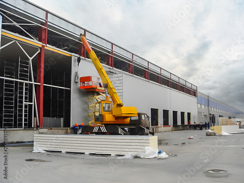 Construction of a modern logistics warehouse with sandwich panels and heavy machinery