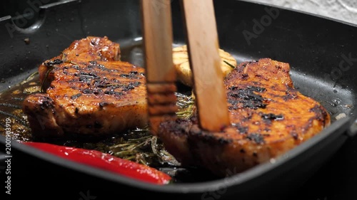 Chef flips a delicious steak with cooking tongs