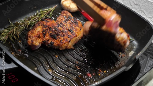 Chef flips a delicious steak with cooking tongs