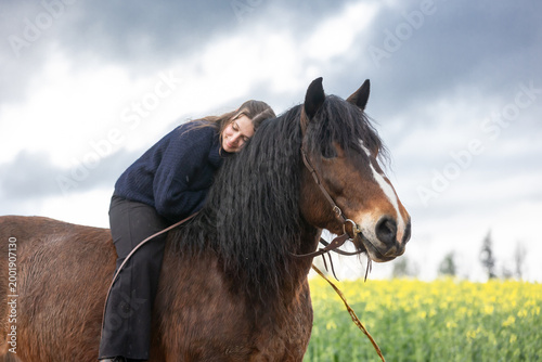 Portrait Frau mit Pferd vor Raps und Gewitterwolken