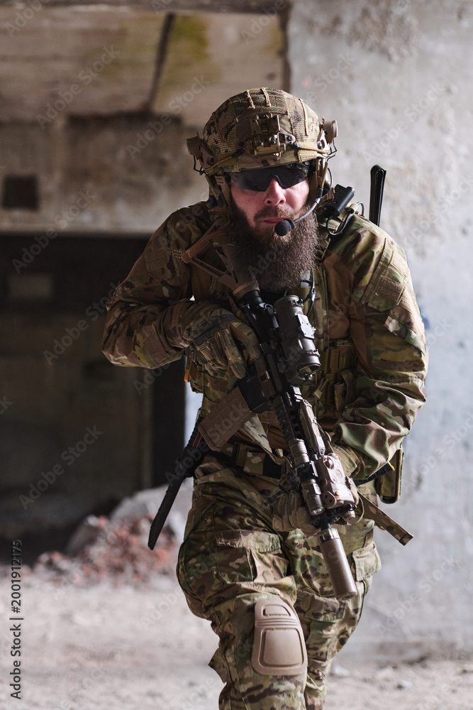 Fototapeta premium Bearded Special Forces Soldier In Tactical Gear Moving Through Urban Combat Environment With Rifle
