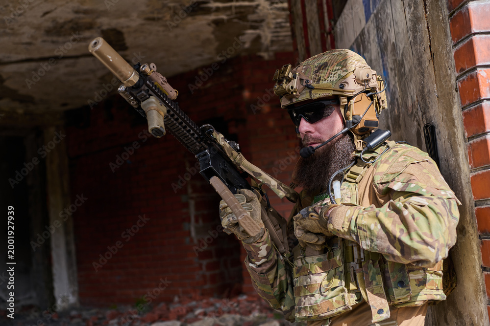 Naklejka premium Bearded Soldier in Tactical Gear With Rifle Conducting Urban Military Operation in Ruined Building