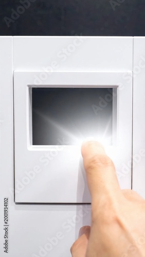 Finger pressing a glowing digital touchscreen display on a white smart control panel for home automation systems, interactive technology