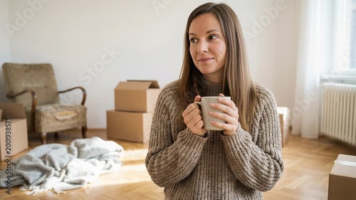 Caucasian woman drinking coffee in new home. Moving day with packing boxes, contemplating plans. Happy concept.