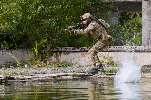 Konstfotografi Soldier in Tactical Gear During Military Training Exercise Near Water With Rifle