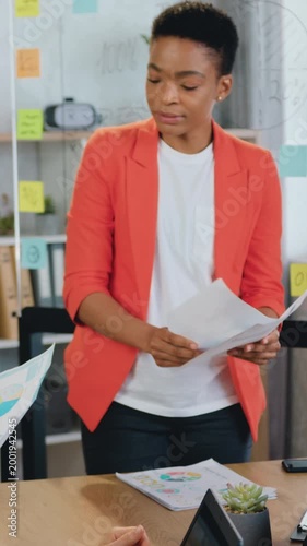 Successful young african american female, checking paper marketing research reports, discussing growth strategy with diverse caucasian businesswomen teammates at t briefing table in office