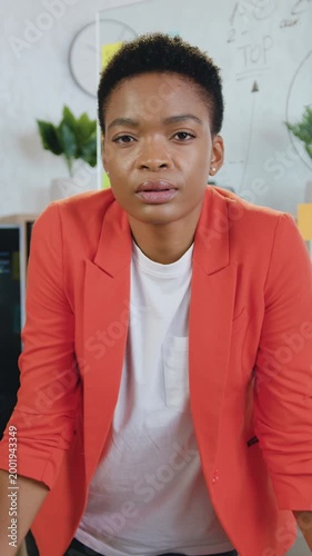 Corporate leader of beautiful african american woman, professional manager employee, standing in modern office looking at camera during briefing table in office. Slow motion