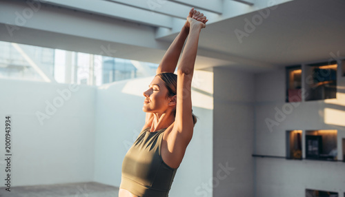 Woman Stretching Arms Overhead in Sunny Minimalist Studio