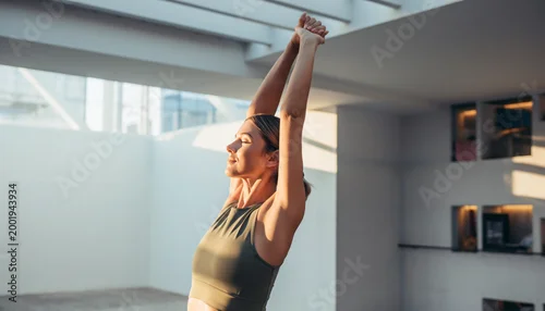 Obraz Woman Stretching Arms Overhead in Sunny Minimalist Studio