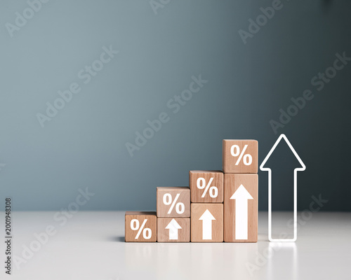 A stack of wooden blocks with percentage signs and arrows indicating growth and increase on a white surface