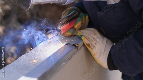 Welder Finishing Seam With Torch And Careful Hand Control, Sparks And Smoke Rising Closeup Of Bead Smoothing And Surface Cleaning On Structural Steel, Gloved Hand And Protective Clothing