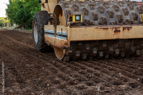 Construction worker operating a tamping rammer machine for soil compaction on site