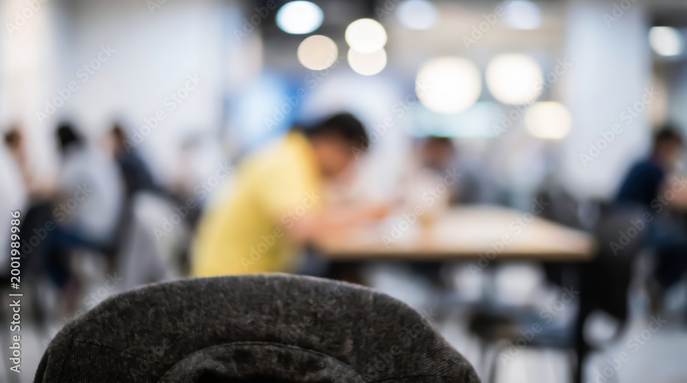 Fototapeta premium Blurred view of people sitting at tables in a modern office cafeteria or coworking space