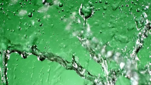 Two glistening water droplets cascade down a vibrant green surface, creating a captivating visual of fluidity and texture.