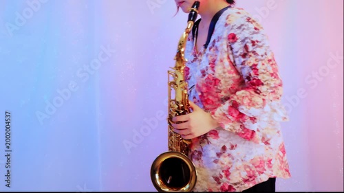 テナーサックスを持って立って体を揺らしている女性：青とピンク色の白背景