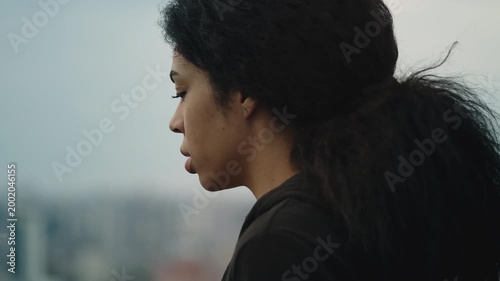 Sad African American woman looking at city from high rise building, acrophobia