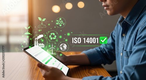 ISO 14001 environmental management system concept. Business professional using digital tablet with sustainability, recycling, CO2 reduction, and renewable energy icons. 