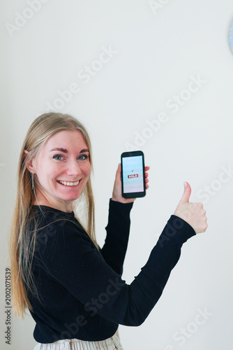 Happy woman presenting a phone screen with sold status. Mobile commerce, resale app and modern digital lifestyle with copy space